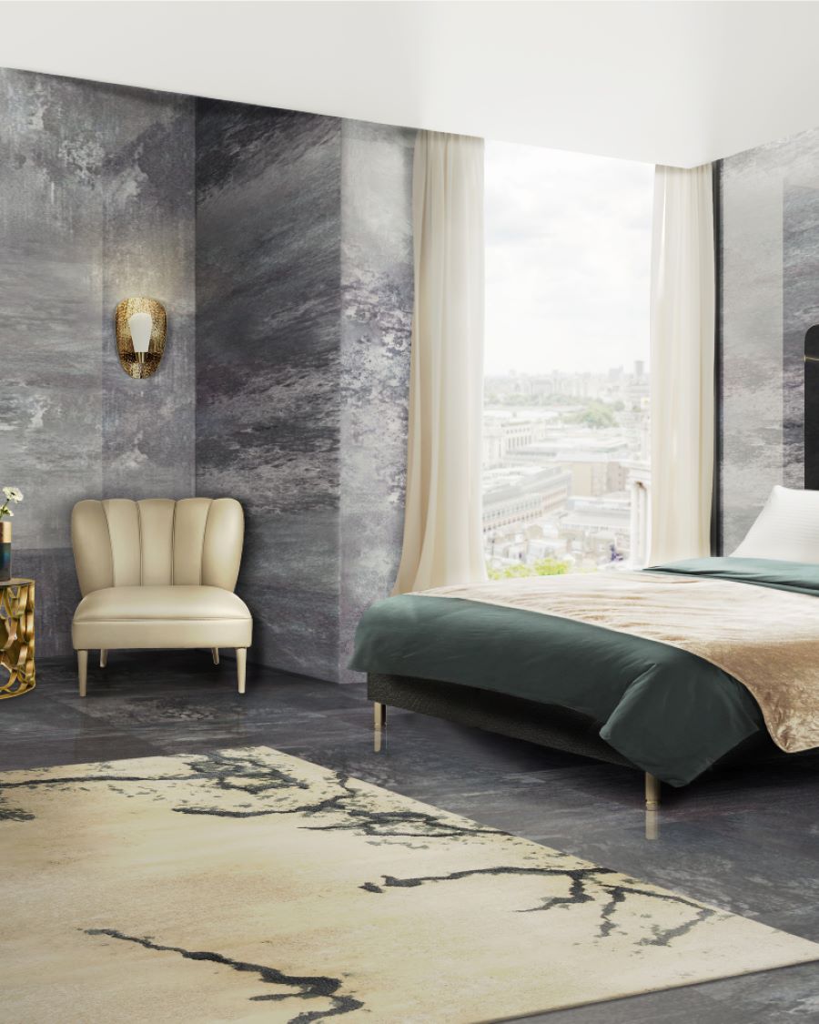Grey hotel bedroom with a bege armchair , a gold side table and blue sheets