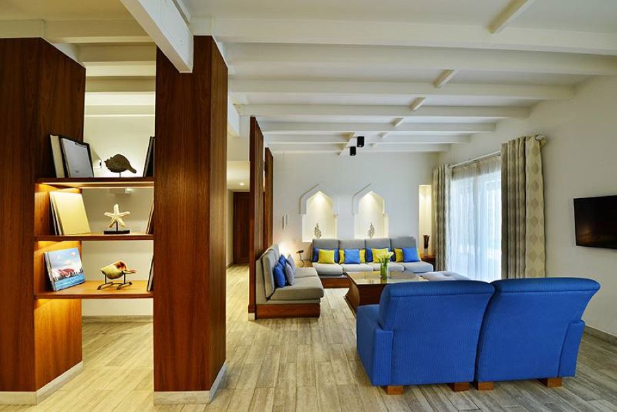 living room hotel, with blue and grey sofas with yellow, blue and grey pillows and a brown center table made of wood.