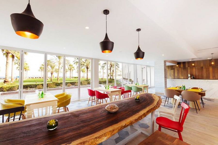 Restaurant Hotel with yellow, red, white, green and brown chairs, a table made of wood, design by Decorelle