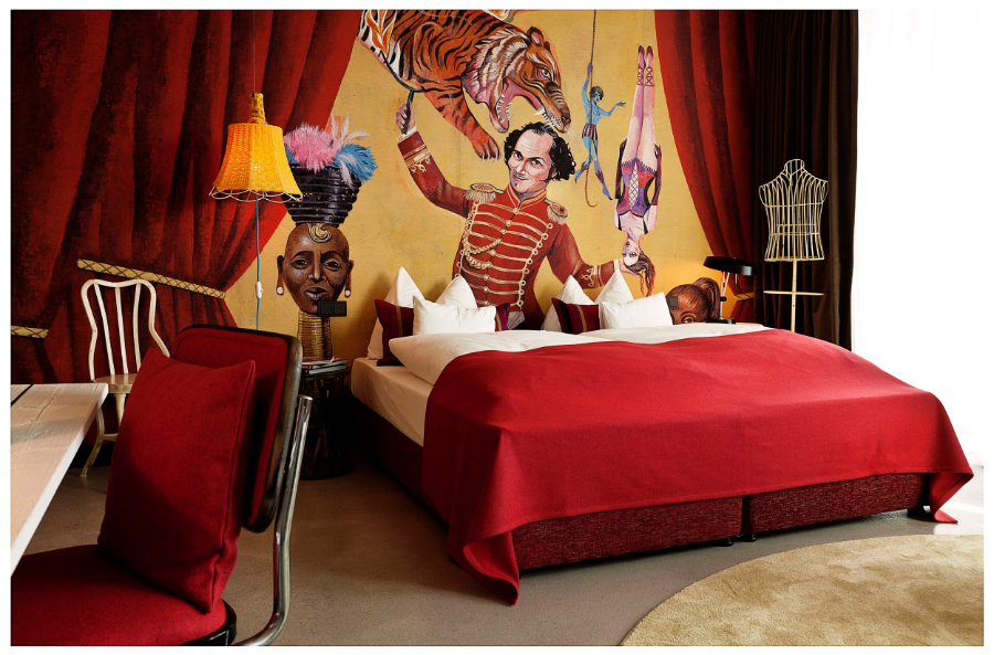 25 hours Hotel Wien red bedroom with a clown paiting.