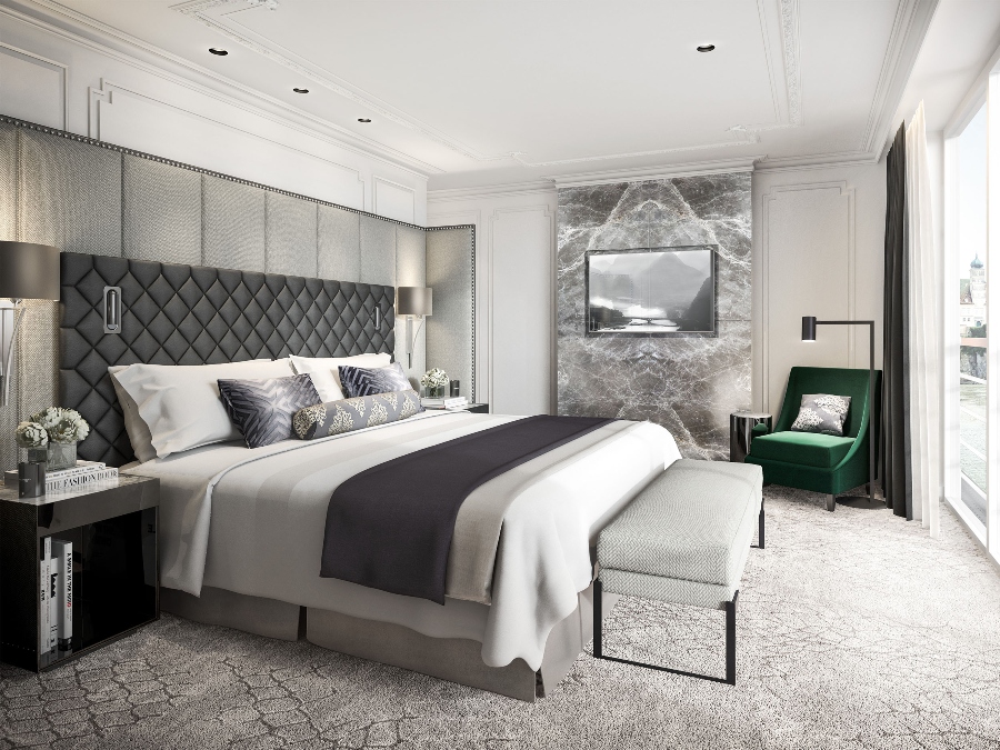 Hotel Decoration With II BY IV DESIGN. The Crystal Mozart hotel bedroom is in grey colors like the fireplace, the bedframe and to contrast a green armchair.